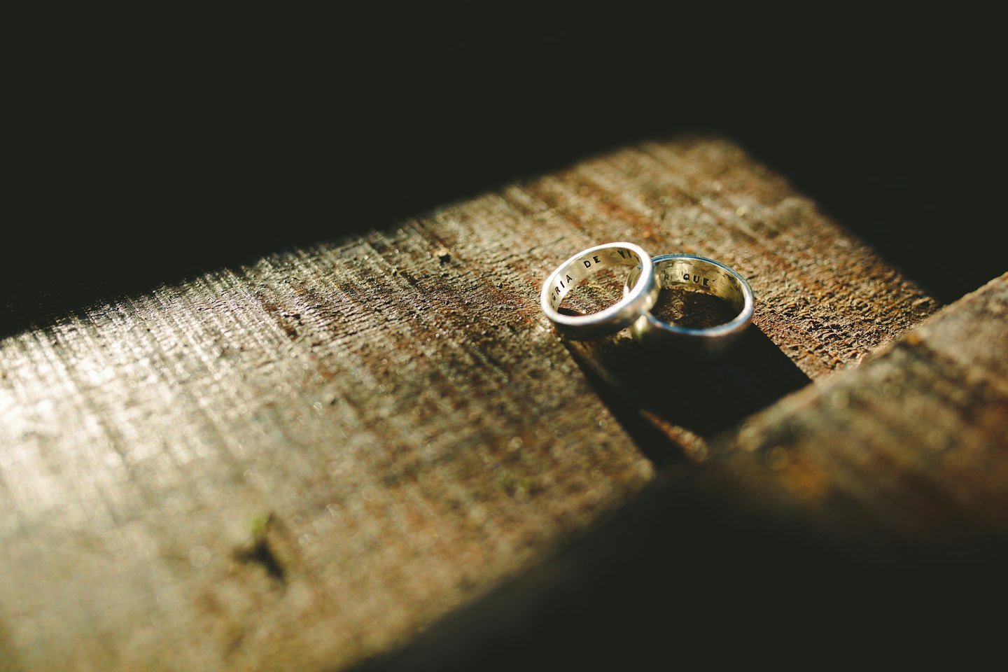 Two silver wedding rings on a wooden surface.