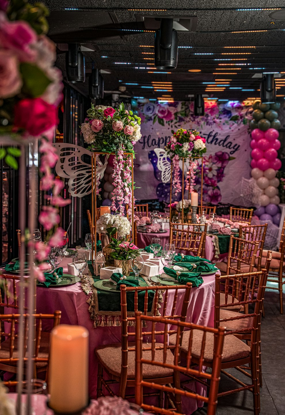 Round tables with pink cloths and floral centerpieces at a party.