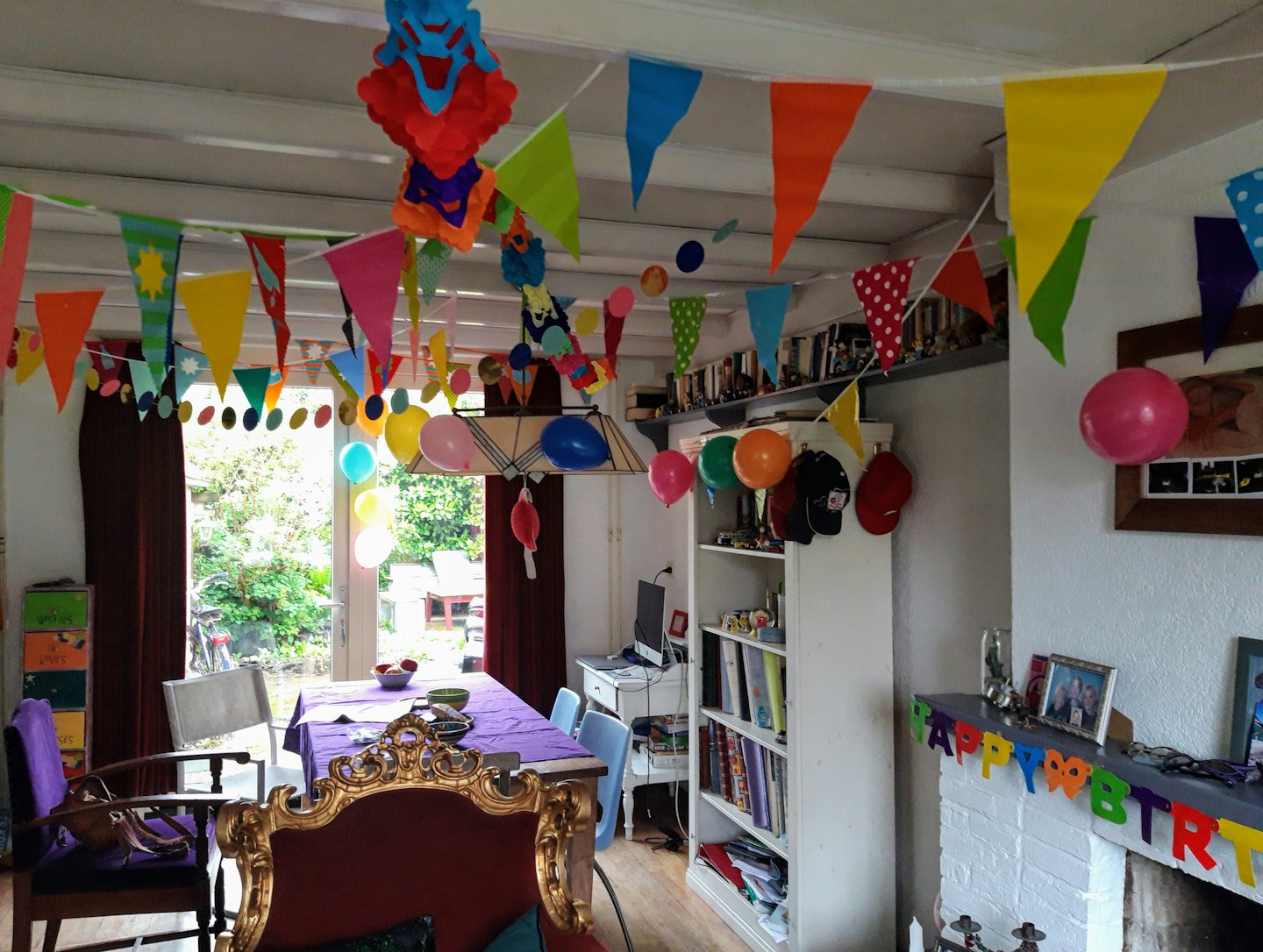 Living room decorated for a birthday with banners and balloons.