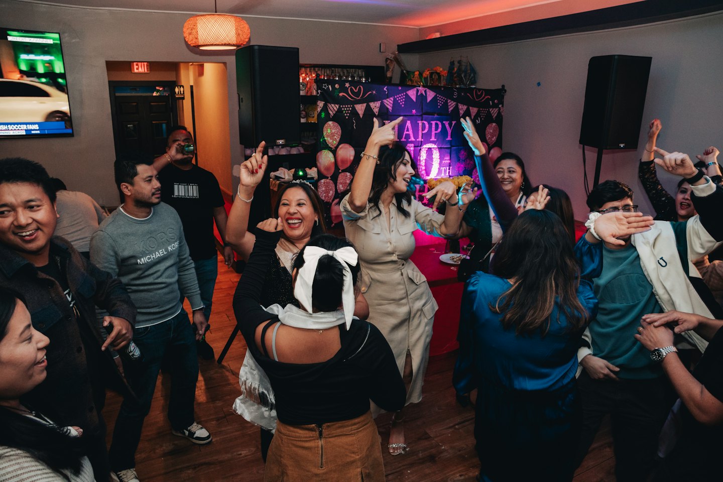 Diverse adults happily dancing and celebrating at an indoor event.