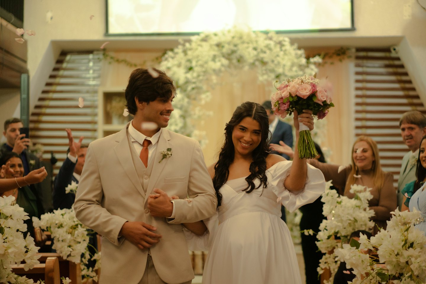 Bride and groom walk down the aisle as petals fall.