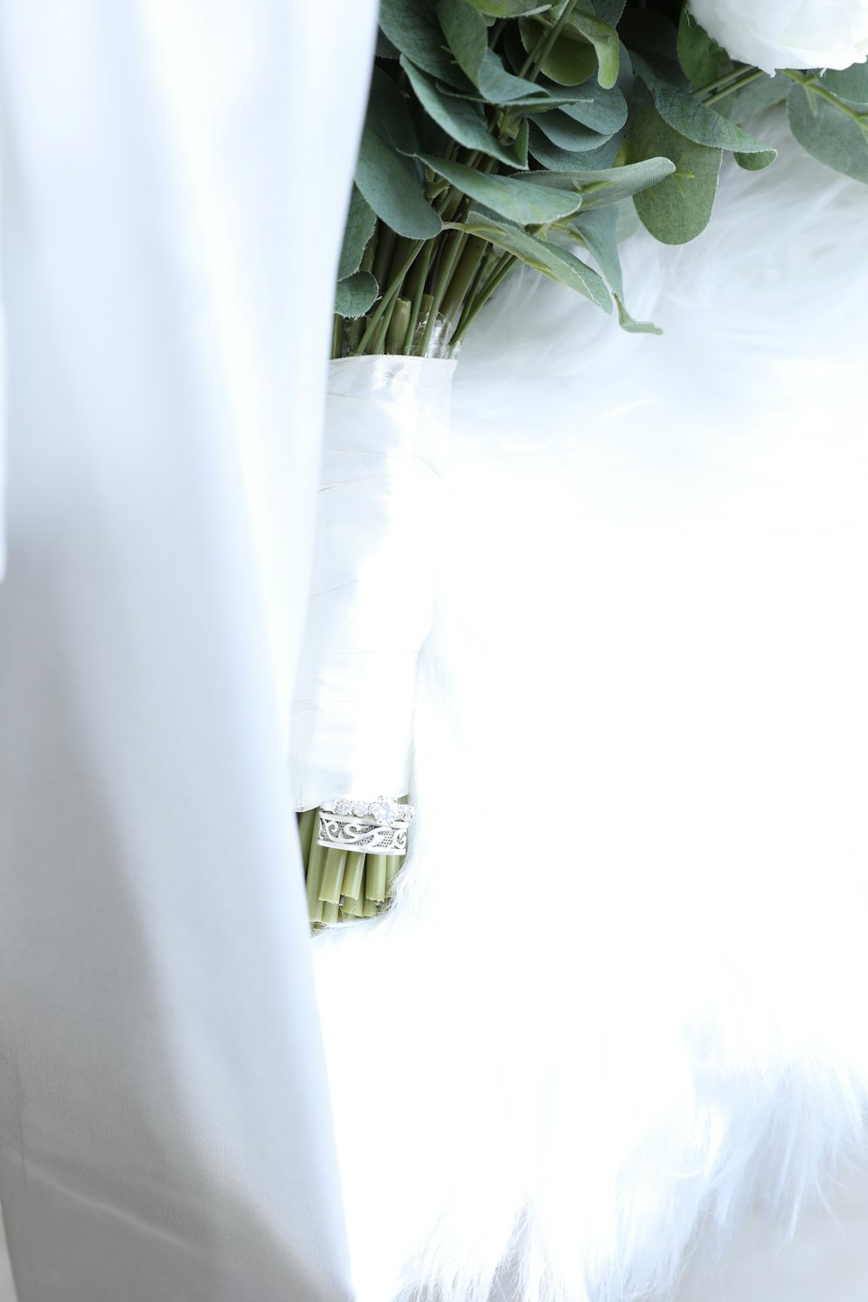 Two silver wedding rings rest on a bouquet of white flowers.